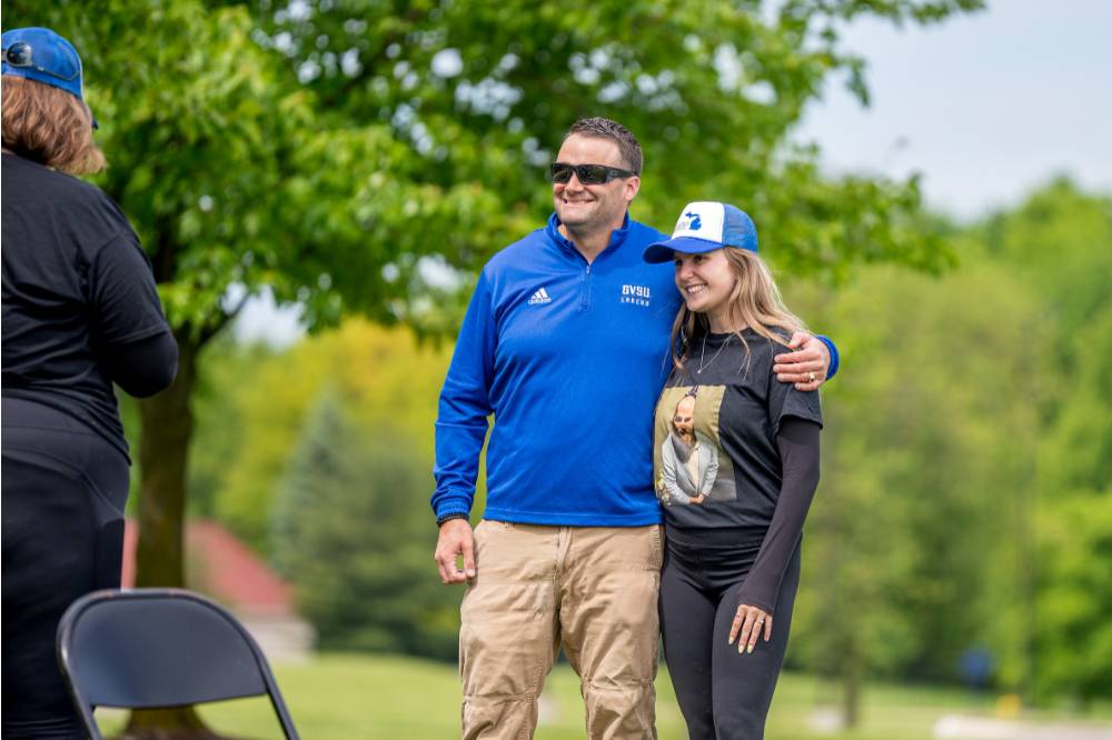 Two players smile and hug while watching a game
